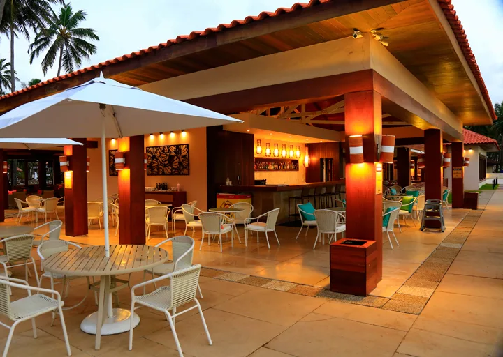 Jatiúca's Areia Fofa Bar, an open kiosk with umbrellas and tables, by the pool
