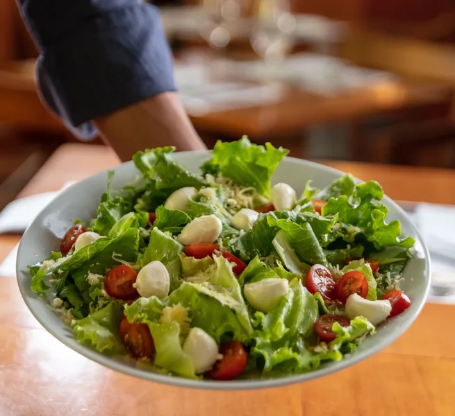 Salada verde com mussarela de búfala e tomate, servida no ¡Vení! Parrilla