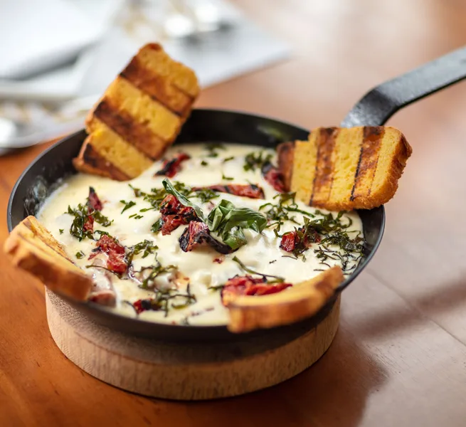 Provolone gratinado com ervas e polenta grelhada, na panela de ferro do ¡Vení! Parrilla