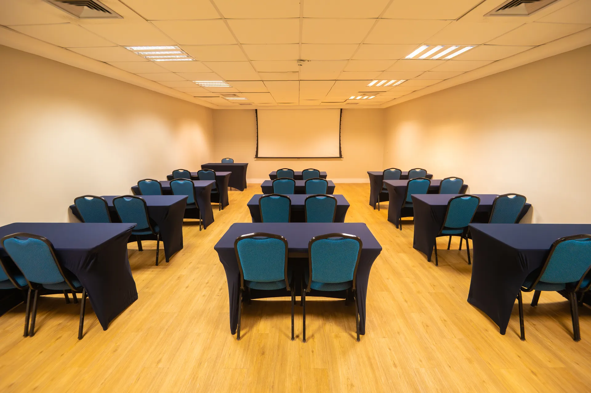 Salón Ipioca armado en formato escolar, con mesas y sillas orientadas hacia la pantalla