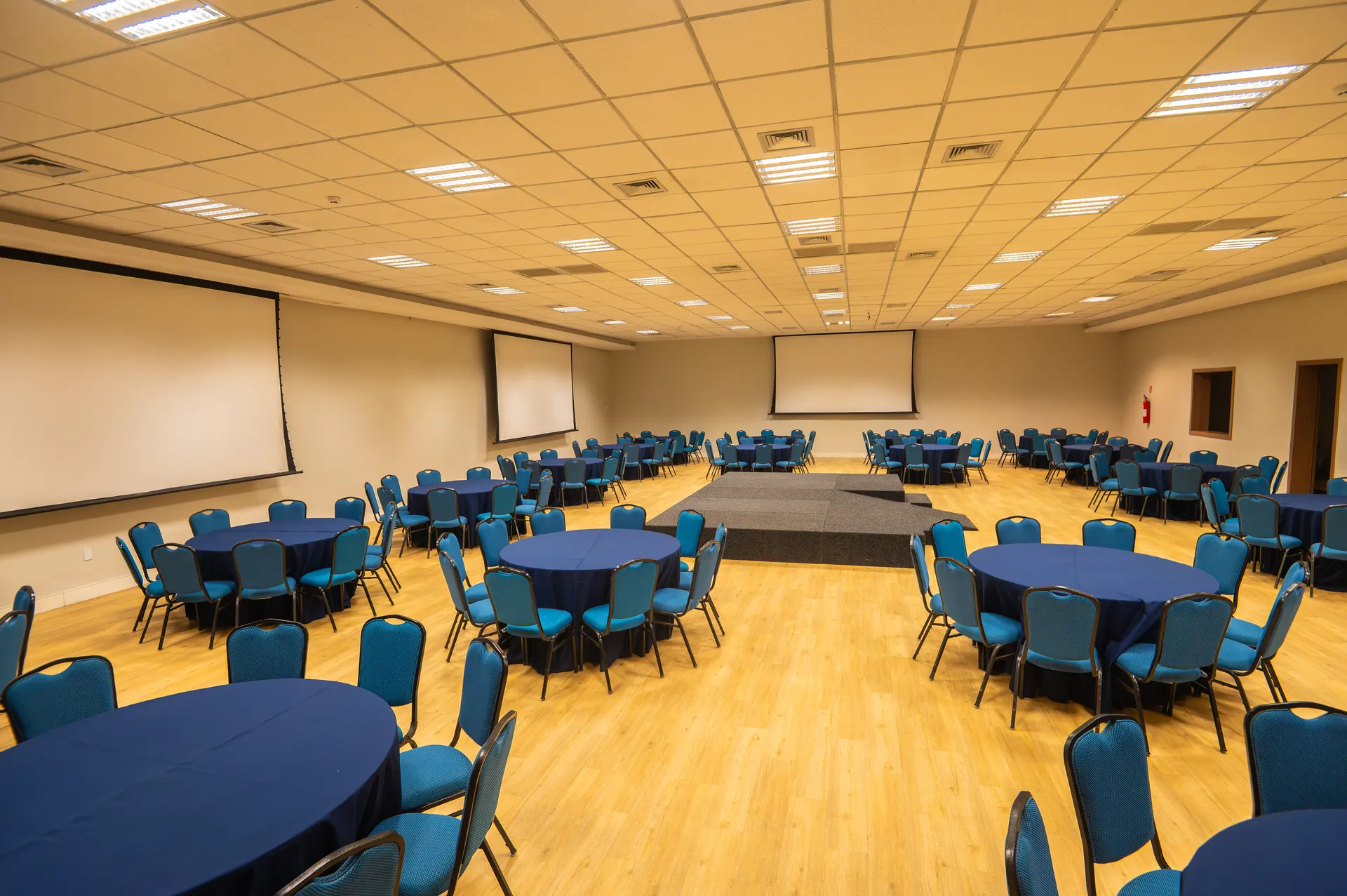 Salón Jatiúca armado con mesas redondas y escenario, en el espacio más grande del Centro de Eventos