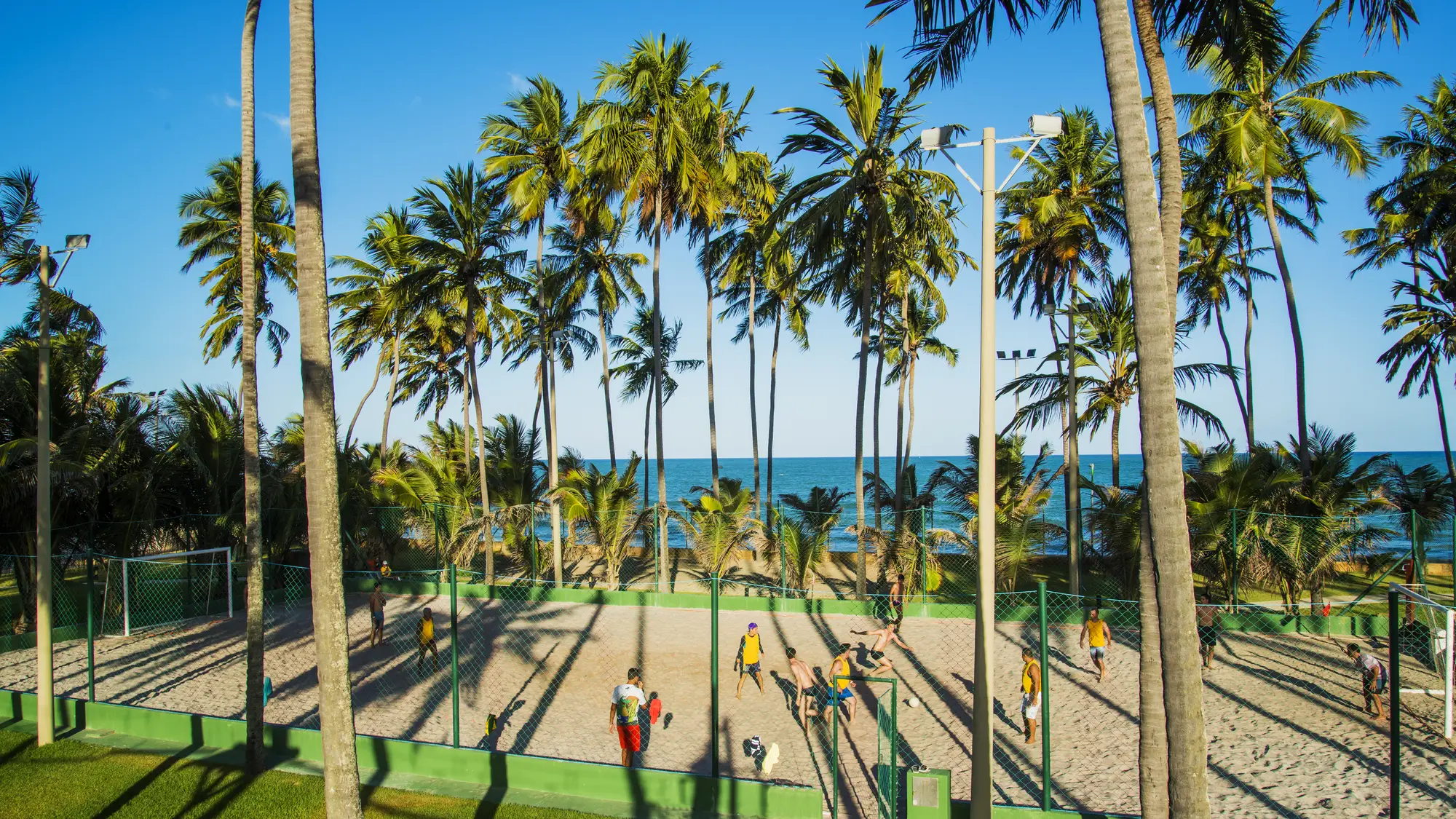 Jatiúca's sand courts in use in the late afternoon, amid the coconut grove, with the sea in the background