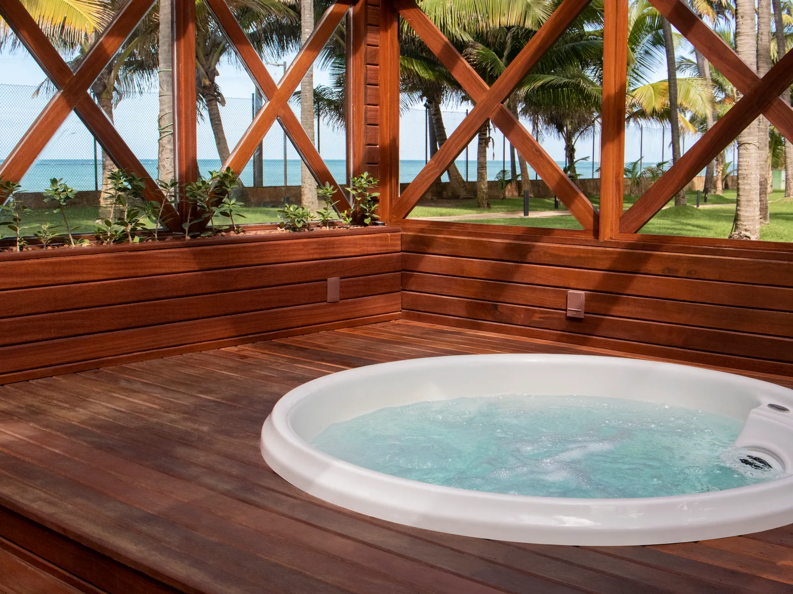 Hydromassage tub at the Jatiúca Spa on a wooden deck, beneath the coconut grove